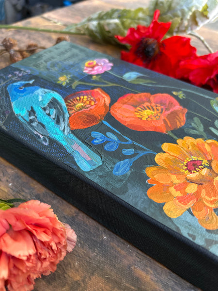 Painting of Indigo Bunting surrounded by orange poppies and zinnias.
